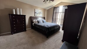 Ein Schlafzimmer mit Bett, Kommode und einem Bild an der Wand.