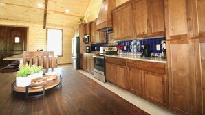 Un intérieur en bois comprenant un coin cuisine, avec des placards, un four à micro-ondes et une table à manger avec des chaises.