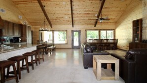 Un vaste espace de vie doté d’un plafond en bois, d’un comptoir de bar et d’un coin salon avec un canapé et des fauteuils.