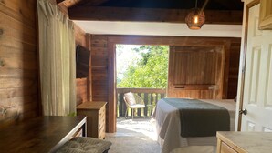 A wooden cabin room with a bed, a desk, and a small table. - Cozy Cottage near Bigfork overlooking Flathead Lake in our Cherry Orchard (Bigfork)