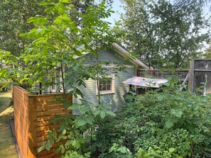A wooden fence, a house with a window, and a wooden deck. - Cozy Cottage near Bigfork overlooking Flathead Lake in our Cherry Orchard (Bigfork)