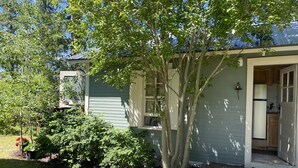 A house with a front porch, a small garden, and a visible kitchen area. - Cozy Cottage near Bigfork overlooking Flathead Lake in our Cherry Orchard (Bigfork)