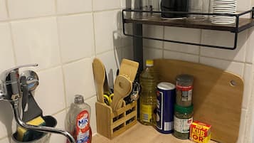 Una cocina con un lavamanos de acero inoxidable, una tabla de cortar de madera y diversos utensilios y electrodomésticos.