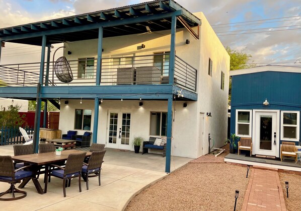A two-story building with a covered patio, outdoor seating, and a small garden area.