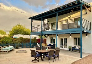 A covered patio with a dining table and chairs, a hanging chair, and a small fire pit. - Cozy, Modern Tiny Home, 1-bed, 1 bath - 10 minutes from UofA & other hotspots! (Tucson)