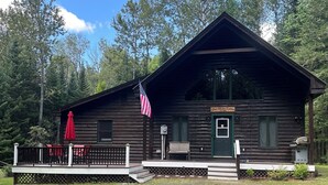 A wooden cabin with a porch, an American flag, and a sign reading "The Meier Cabin."