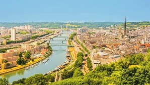 Un paisaje urbano con un río, edificios y una torre destacada.