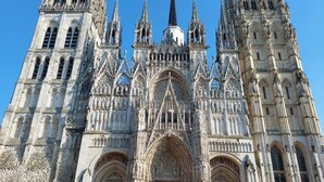 Una catedral gótica con elaborados detalles de piedra, grandes entradas arqueadas y múltiples torres.