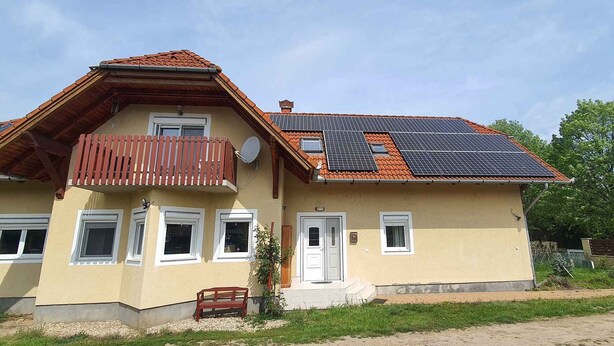 Een twee verdiepingen tellend huis met een schuin dak, zonnepanelen en een balkon.