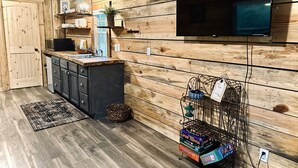 Una cocina con paredes de madera, un televisor de pantalla plana y una cafetera.