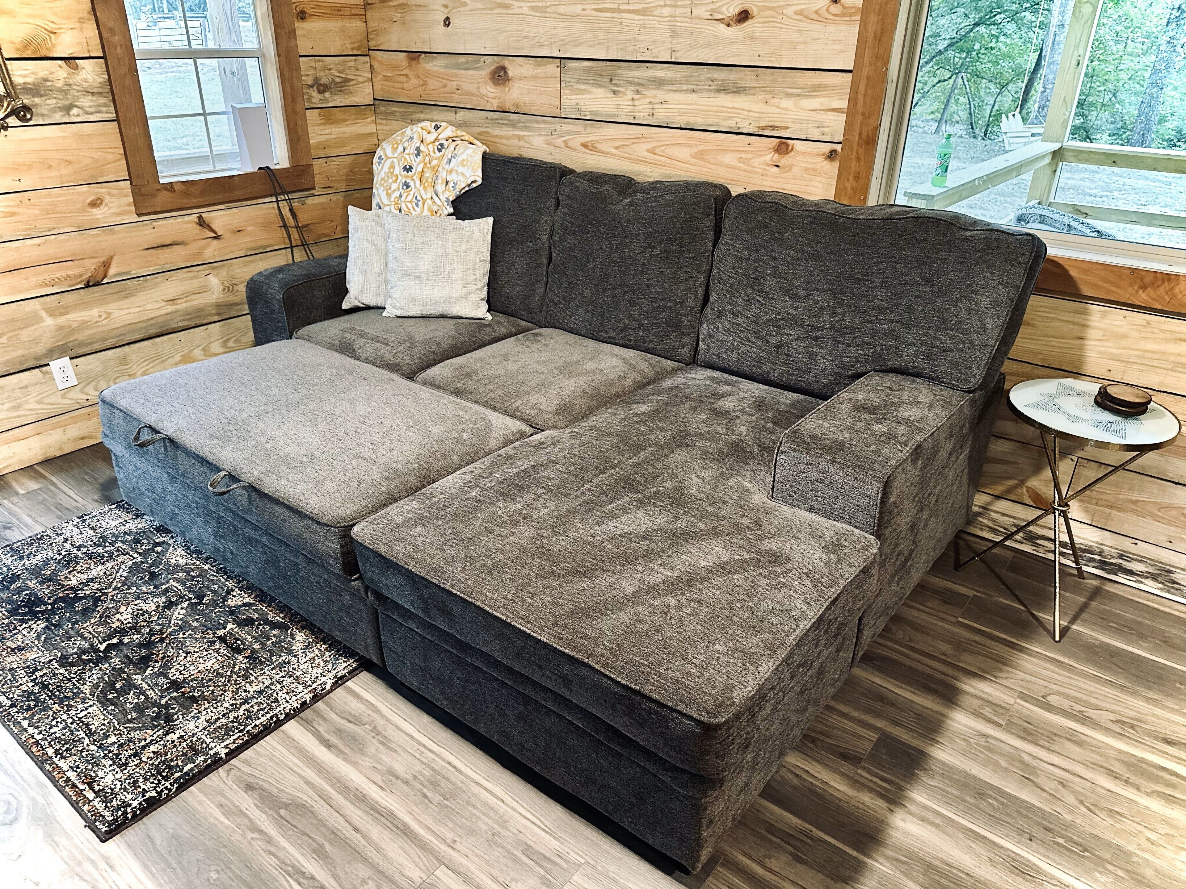 A modern log cabin interior with a sectional sofa, a small round table, and a patterned rug.