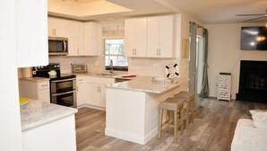 Una cocina moderna con armarios blancos, microondas, horno y una isla grande con taburetes.