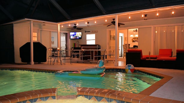 Una piscina interior con hidromasaje, zona de barbacoa y un área de estar con televisor.