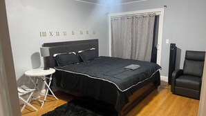 Quarto com uma cama, uma cadeira, uma mesinha e um aquecedor.