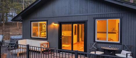 A modern cabin with a deck, large windows, and outdoor seating.
