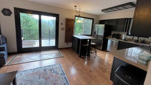 Una cocina moderna con una isla central, un refrigerador y un comedor con vistas a un balcón.