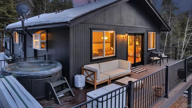 Una cabaña con jacuzzi, terraza y un interior acogedor con ventanas amplias.