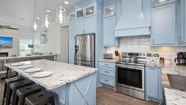 Una cucina moderna con mobili blu, elettrodomestici in acciaio inossidabile e un piano di lavoro in granito.