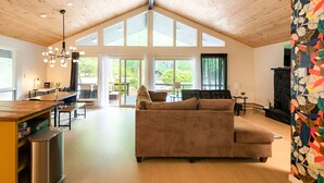 Ein geräumiger Wohnbereich mit hoher Decke, einem Sofa, einem Esstisch und einem Kamin.