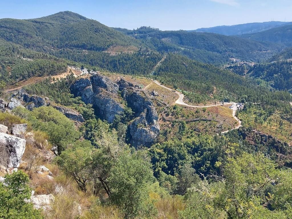 Bjergrigt landskab med slyngende vej og tæt skov.