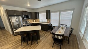 A modern kitchen with dark cabinets, stainless steel appliances, and a central island with bar stools. - Beautiful Modern Lake House Along Lake Oahe. (Pierre)