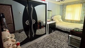 Une chambre à coucher avec un lit, une commode, un miroir et un sol carrelé.