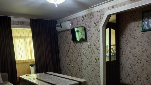 Une pièce comprenant un lit, un canapé, une télévision et un tapis à motifs.