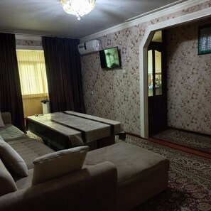 A room with a bed, a sofa, a TV, and a patterned carpet. - Relax Diamond APT (Kutaisi)