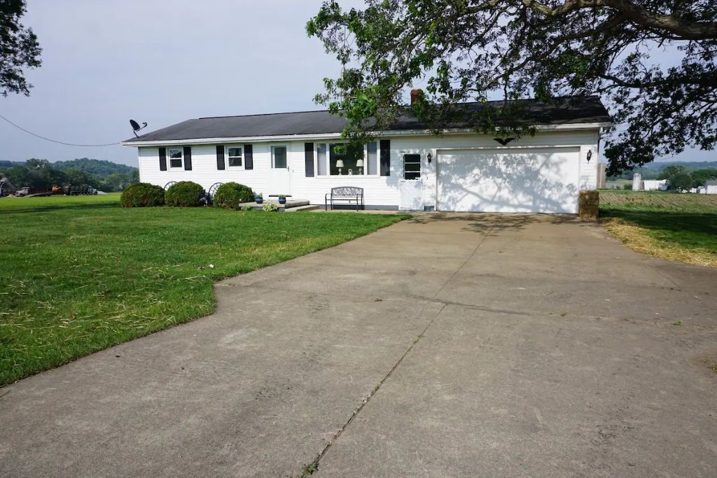 A white single-story house with a front porch, a garage, and a well-maintained lawn.