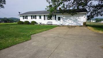 A white single-story house with a front porch, a garage, and a well-maintained lawn.