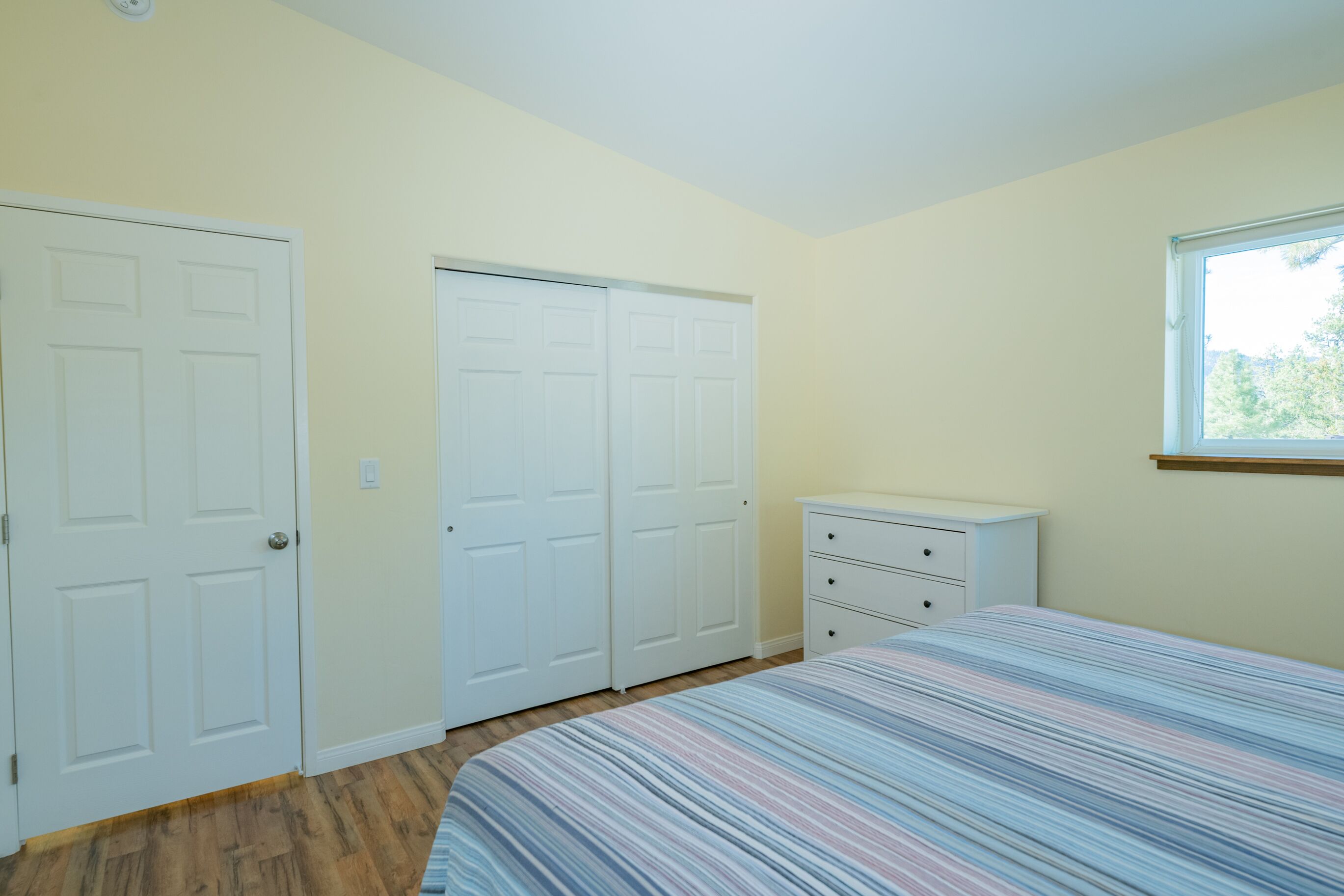 Un dormitorio con una cama, un aparador y dos armarios.