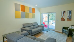 A modern living room with a sectional sofa, a glass coffee table, and a large window with a view of the outside. - Modern Times (Big Bear Lake)