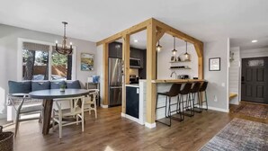 Een moderne keuken met een houten kookeiland, barkrukken en een eethoek met een ronde tafel en stoelen.