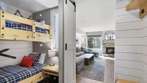 Een kamer met stapelbedden, een slaapbank, een open haard en uitzicht op de omgeving.