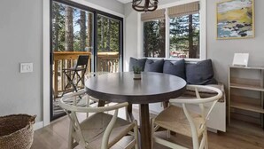 Een eethoek met een ronde tafel, witte stoelen en een bank met kussens.