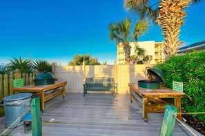 A wooden deck with a bench, a table with a grill, and trash bins. - Windy Hill Dunes-Oceanfront 3BD-Family Friendly (North Myrtle Beach)
