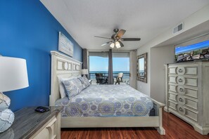 A bedroom with a bed, a dresser, a nightstand, a ceiling fan, and a view of the ocean. - Windy Hill Dunes-Oceanfront 3BD-Family Friendly (North Myrtle Beach)