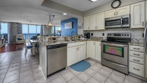 A modern kitchen with white cabinets, stainless steel appliances, and a blue accent wall. - Windy Hill Dunes-Oceanfront 3BD-Family Friendly (North Myrtle Beach)