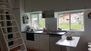 A compact kitchen with white cabinets, a built-in dishwasher, a sink, and a window providing a view of the outdoors.