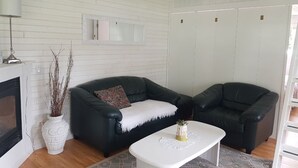 A living room with a fireplace, two black leather sofas, a white coffee table, and a white cabinet with sliding doors.