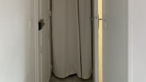 Un pasillo estrecho con una puerta blanca a la izquierda y una cortina color beige a la derecha.