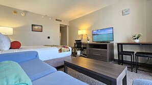 Una habitación de hotel con una cama, un escritorio con televisor, una silla y un sofá.