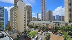 Un edificio residencial de gran altura con varios pisos, un estacionamiento con distintos automóviles y edificios de gran altura circundantes.