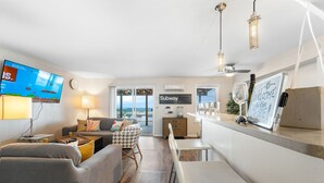 Una sala moderna con un sofá, una mesa de comedor y un televisor montado en la pared.