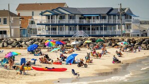 Una propiedad frente a la playa con un edificio de varios pisos, una playa de arena y un litoral rocoso.