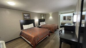 A hotel room with two beds, a desk, a chair, a mirror, and a radiator. - Royal Inn Motel (Fredericksburg)
