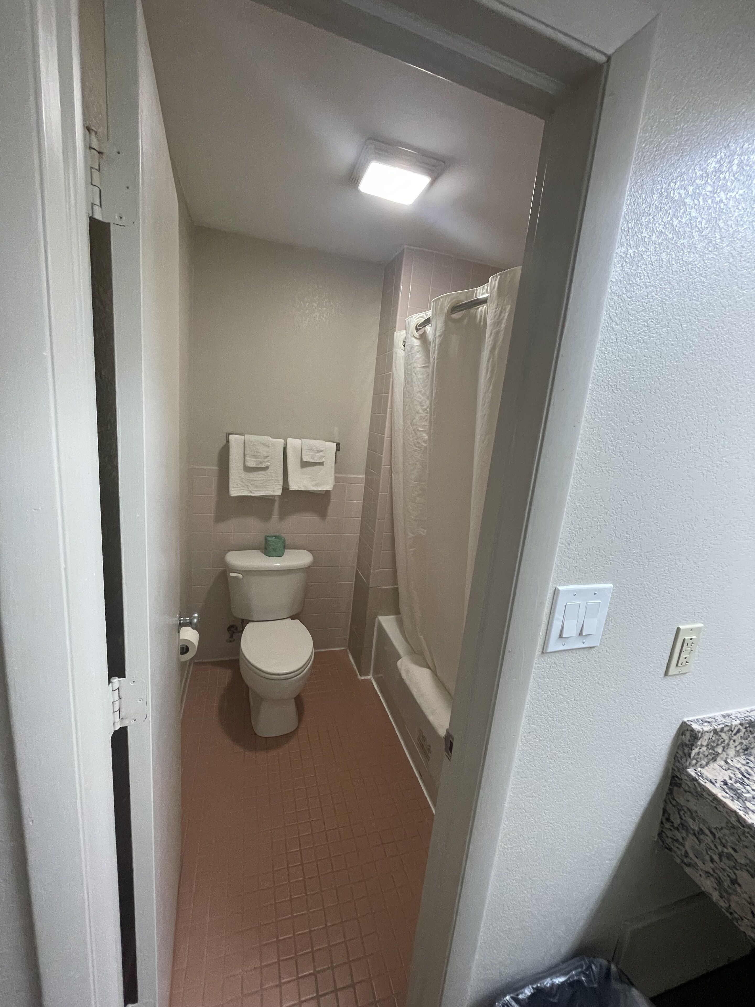 Une petite salle de bain avec des toilettes, un rideau de douche et un porte-serviettes.