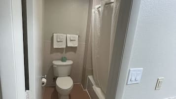 A small bathroom with a toilet, a shower curtain, and a towel rack.