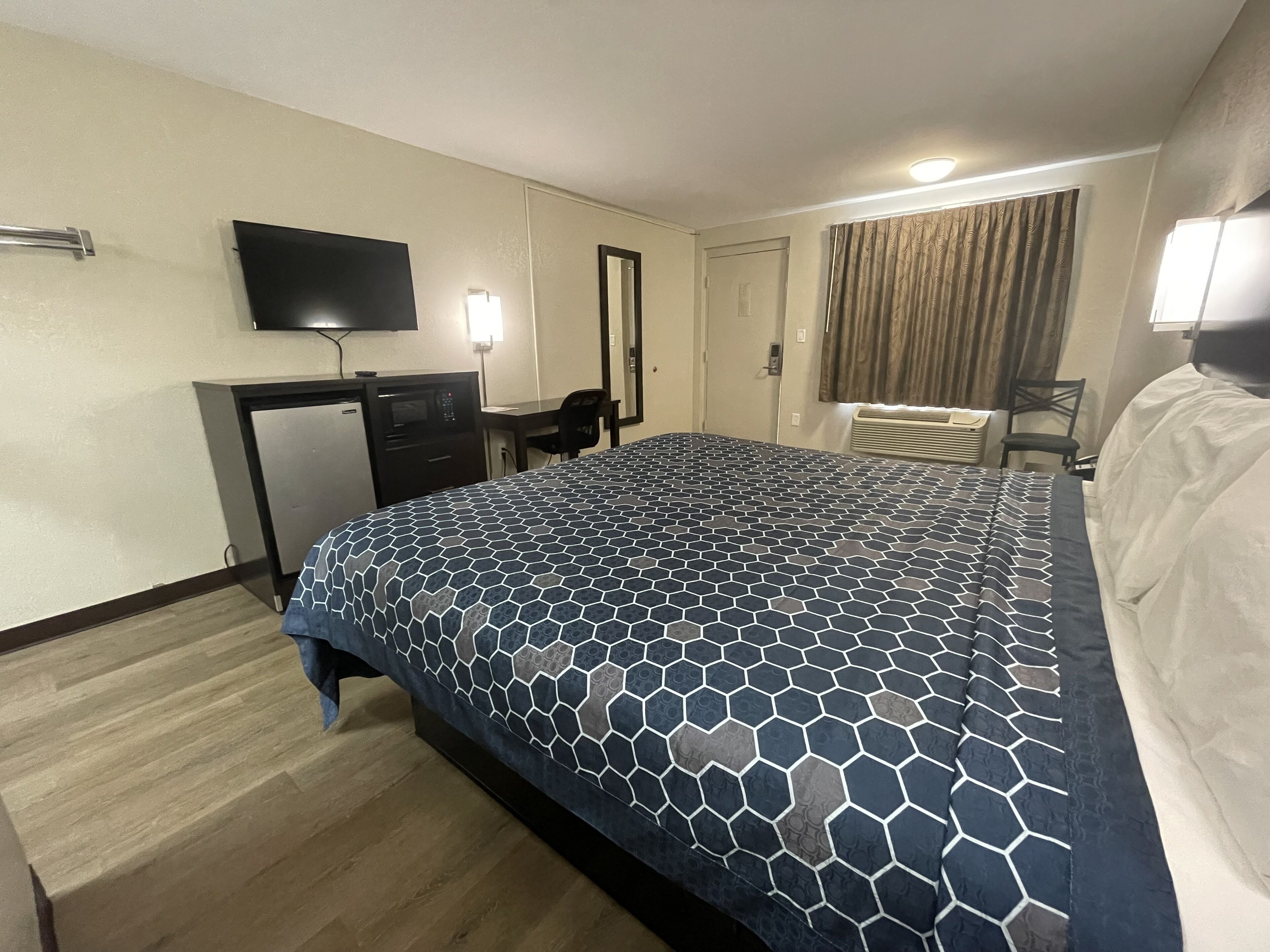 A hotel room with a bed, desk, and television.
