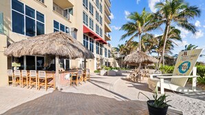 A hotel with outdoor seating, palm trees, and a sign for Marriott Palm Beach Singer Island. - Ocean View 1 Bedroom Condo (Singer Island)
